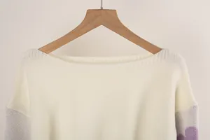 Close-up detail of white off-the-shoulder knitted sweater with purple floral sleeves