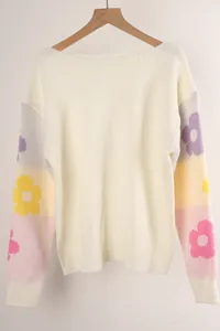 Close-up of a white knit sweater with colorful floral patterns on color-blocked sleeves