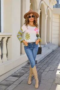 Lifestyle view of a floral and striped knit sweater styled with denim and tall boots.