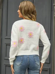 Detail view of white knit sweater featuring pink daisy floral patterns on the back