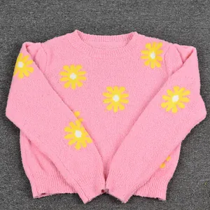 Detailed view of the pink knit sweater with vibrant yellow daisy patterns