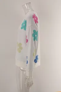 Side view of white knit sweater with colorful flower patterns and crewneck design