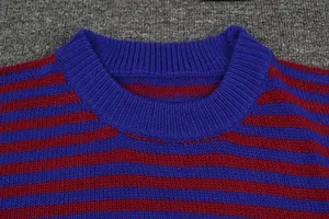 Gedetailleerde close-up van de geribbelde halslijn en textuur van een blauw en rood gestreepte trui