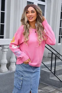 Detailed view of pink oversized knit sweater with colorful flower patterns on sleeves