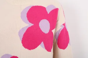 Macro detail of a beige crew neck sweater with vibrant pink floral knit patterns.