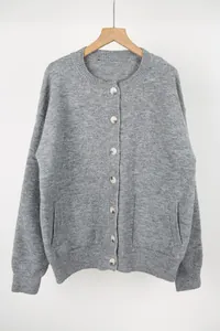 Close-up detail of a grey knitted cardigan featuring round neck and amber textured buttons