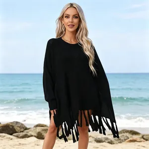 Close-up detail of black knitted beach cover-up with long decorative fringe hem.