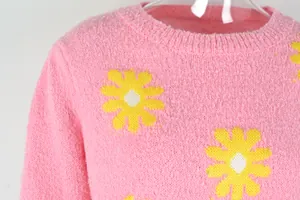Close-up of pink knit sweater with yellow daisy flower patterns showing texture