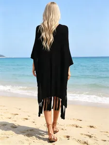 Back view of a black oversized hollow-out beach cover-up with tassels on the beach