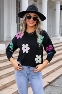 Close-up view of a black knit sweater featuring vibrant colorful flower patterns