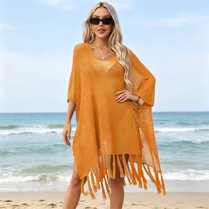 Close-up of orange knit beach cover-up with hollow-out pattern and tassel hem detail