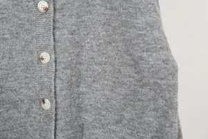 Detail view of a grey knitted cardigan featuring marble-texture buttons and soft fabric.
