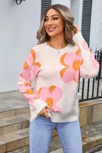 Outdoor lifestyle shot of a woman in a white round neck sweater with large pink floral prints.