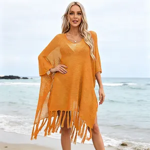 Women's yellow knitted hollow-out beach cover-up with tassel hem in a beach setting.