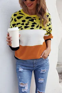 Woman in color-block leopard print sweater and distressed jeans holding a coffee cup