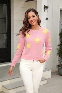 Detailed view of pink knitted sweater featuring vibrant yellow daisy floral patterns