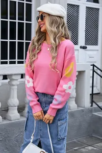 Stylish model wearing a pink loose-knit sweater with floral patterns on sleeves outdoors