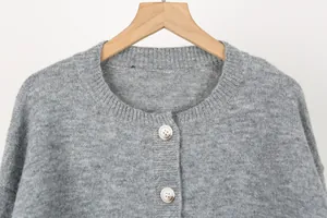 Close-up detail of a grey knitted round neck cardigan featuring stylish textured buttons
