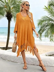 Outdoor beach setting showing an orange knit cover-up with stylish tassels on a model