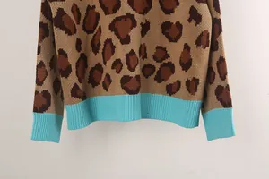 Close-up view of leopard print knit sweater featuring turquoise ribbed hem and cuffs