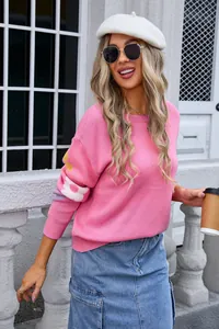 Close-up of pink knit sweater showing floral pattern on sleeves and wide neckline