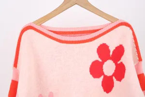 Close-up of pink knit sweater with red flower pattern and detailed neckline texture