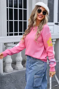 Detailed shot of a pink loose knit sweater with vibrant floral patterns on the sleeves