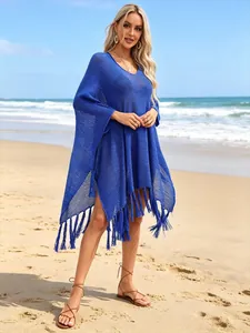 Vibrant blue knitted beach cover-up featuring V-neck and long tassel hem on sunny beach