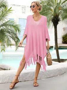 Detailed view of pink crochet beach cover-up with tassel fringe in sunny resort setting