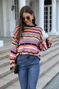 Elegante maglione traforato a righe colorate indossato da una modella all'aperto.