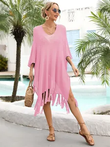 Stylish pink hollow-out knit beach cover-up with tassel trim shown at a resort pool