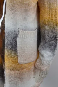Close-up detail of a soft ombre knitted cardigan with a large pocket in yellow and grey.