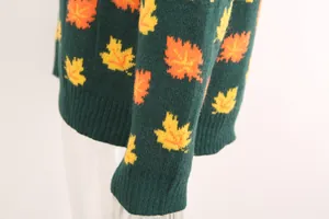 Detailed macro view of the knitted texture and maple leaf patterns on a green sweater