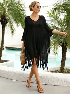 Stylish black crochet beach cover-up with tassel hem in a tropical pool setting.