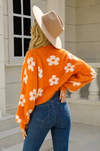 Macro detail of the orange fuzzy knit sweater featuring a white flower pattern on the back