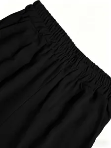 Detalle de la cintura elástica alta en el tejido de unos pantalones anchos negros