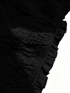 Primer plano de tela fruncida negra con textura elástica y detalle de borde de volante.