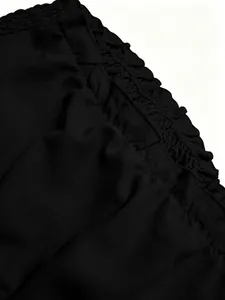 Detalle de cerca de la cintura elástica con volantes de unos pantalones negros de talle alto
