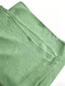 Primer plano de tela texturizada verde salvia que muestra detalles de costura de un conjunto