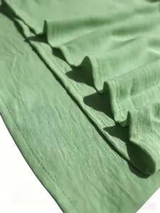 Primer plano de la textura de la tela verde claro y costuras del conjunto de dos piezas