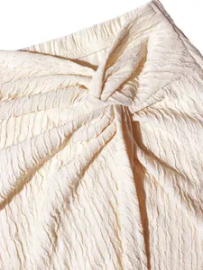 Macro view of cream crinkled fabric texture and knotted design detail on elegant garment