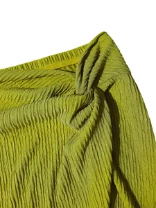 Close-up of green pleated fabric texture with elegant knot detail for summer resort wear.