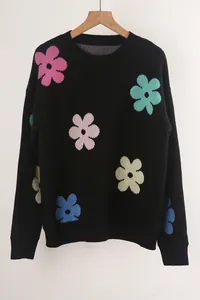 Detailed view of black crewneck knit sweater featuring vibrant colorful flower patterns