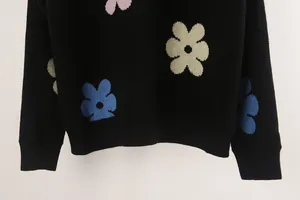 Detailed view of the colorful knitted floral pattern on a soft black knit sweater
