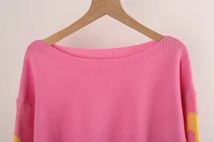 Detail view of pink boat neck knitted sweater featuring floral pattern on sleeves