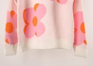 Close-up of the pink knitted sweater hem and sleeve featuring a vibrant orange flower print