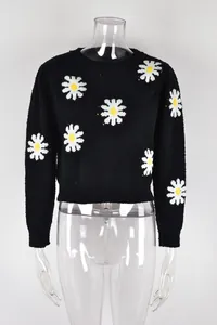 Macro view of black crew neck knitted sweater featuring white daisy floral pattern detail