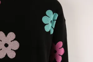 Close-up of a black knit sweater featuring colorful flower patterns and texture