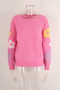 Detailed view of a pink knit sweater featuring vibrant floral patterns on the sleeves