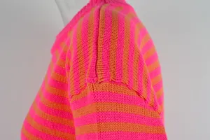 Close-up van levendig neonroze en oranje gestreept patroon op gebreide trui schouder